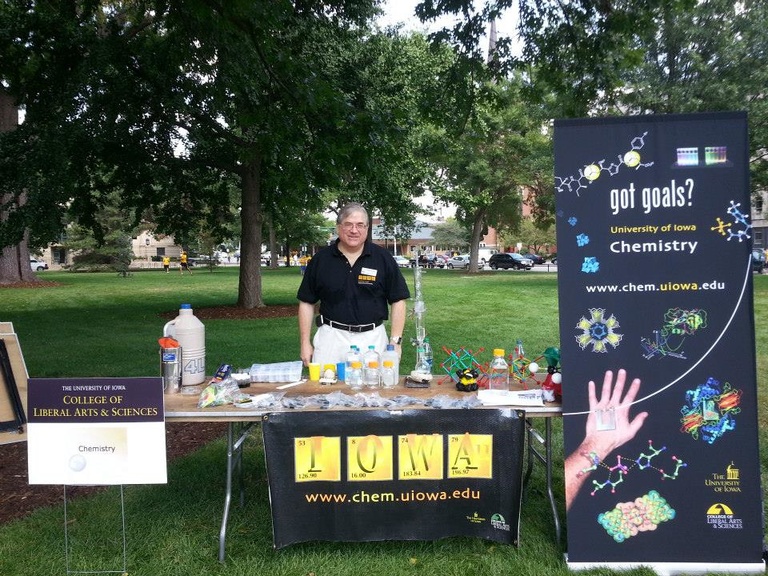 Lou Messerle standing behind an information table for the Department of Chemistry